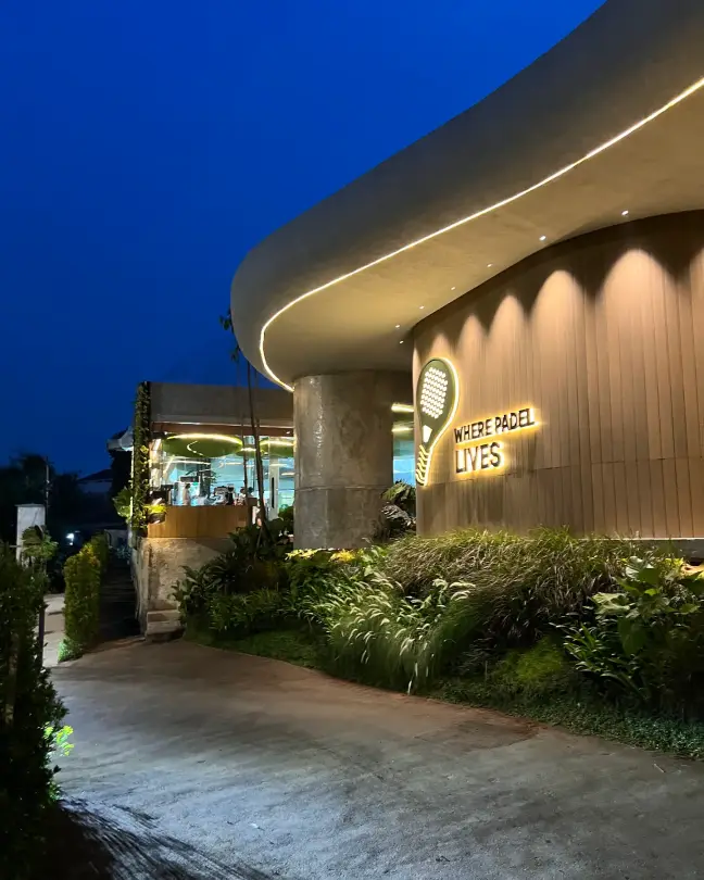The curved entrance and Where Padel Lives sign at dusk